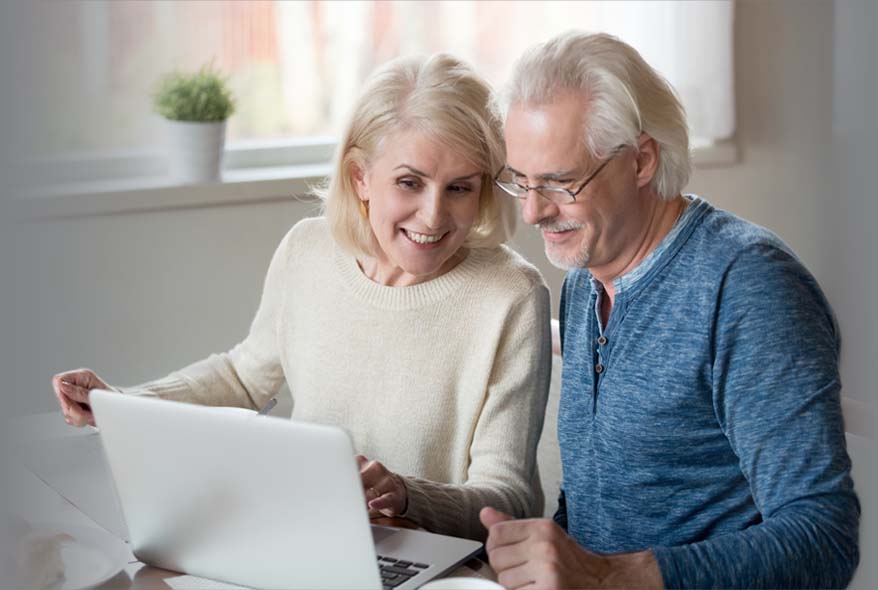 Couple using a laptop to search for Hearing Aid Insurance Coverage by Midwest Hearing Agency
